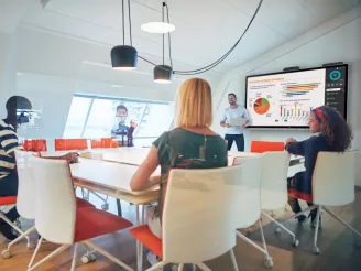 Office workers in a meeting room with an on-screen presentation